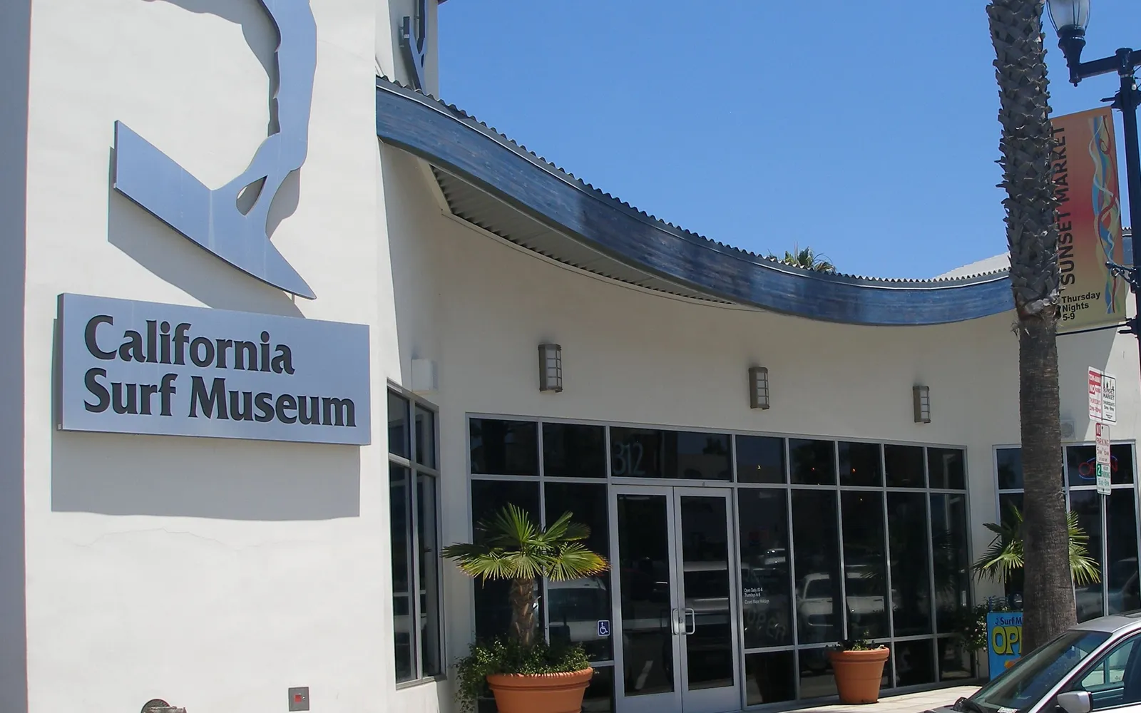 Entrance of the California Surf Museum in Oceanside with its curved blue roofline and surfer sculpture